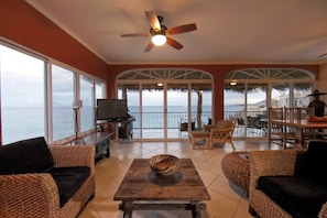 Living room seating area with surrounding windows and views of the ocean.