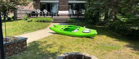 Front of house with firepit, kayaks, and large deck