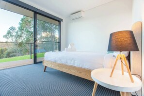  The spacious first bedroom is a light-filled retreat with a king-sized bed, air-conditioning, and sliding doors leading to the deck.