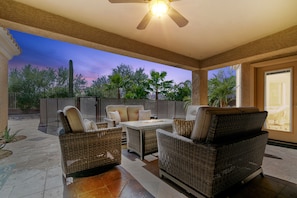 Back Patio: glider seating set with fire table overlooking the pool and views