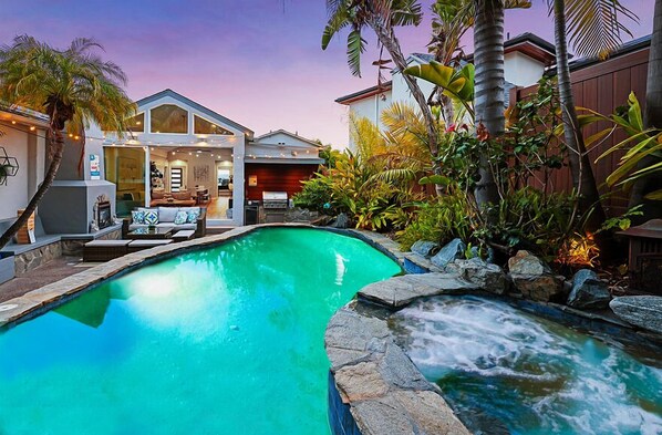 Unwind in your own private oasis featuring a heated pool with a soothing waterfall, a hot tub, and an outdoor lounge complete with a BBQ and fireplace. It's the perfect spot to escape the hustle and bustle