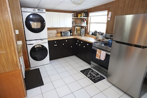 Full sized kitchen stocked with essentials: oil/vinegar, salt & pepper, spices, coffee maker, toaster oven, microwave, pots & pans, dishwashing pods + laundry detergent, etc.