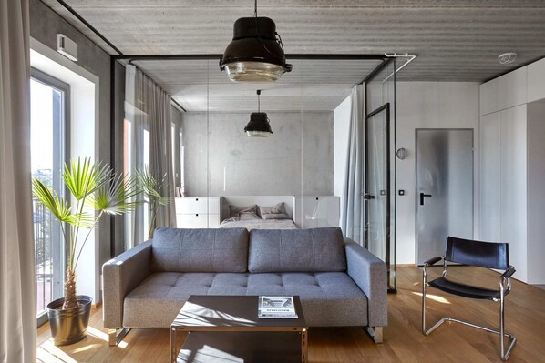 A spacious living room with modern furniture, large windows, and green plants that add a fresh, natural vibe.
