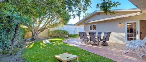 Backyard provides well manicured lawn and cornhole game for guests to play