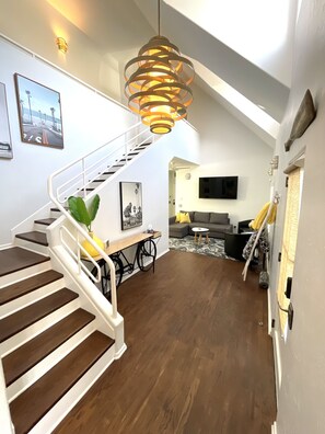 View of smartTV room, front door at right, nautical-inspired staircase at left