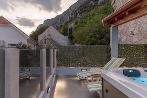 An outdoor terrace with a hot tub, sun beds and seating area