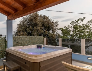 An outdoor terrace with a hot tub, sun beds and seating area