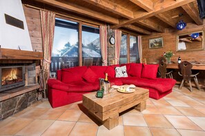 Chalet style lounge with log fireplace, leading onto balcony