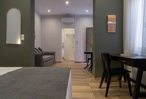 Bedroom with adjoining seating area and doorway to kitchenette 