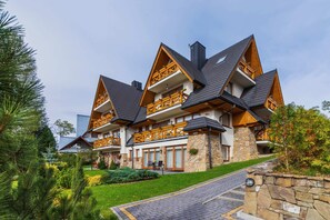 A picturesque chalet-style building with wooden accents surrounded by greenery, blending into the mountain scenery.