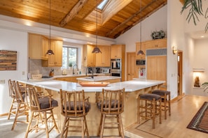 Kitchen, Island with sink, Reg coffee maker, Fire extinguisher, dishwasher, and wrap-around kitchen counter with stools for extra seating.