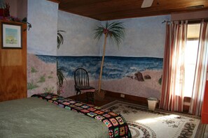 Upstairs bedroom with a full size bed and a tropical theme.  Combined tub/shower