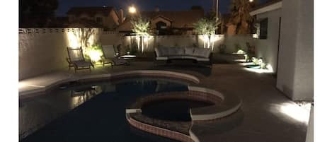 Lighted pool area with lounge furniture,  outdoor grill & seating
