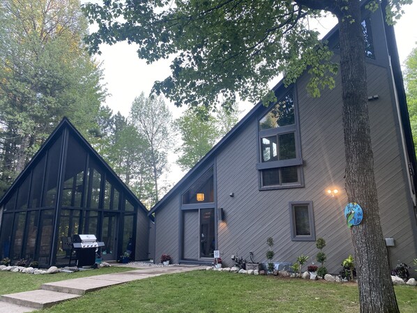 Screened porch area with grill and front entry to home 