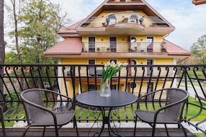 A charming outdoor terrace with a round table and chairs surrounded by greenery. The perfect spot for enjoying a coffee with a view.
