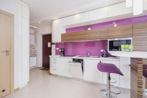 A vibrant kitchen with purple cabinetry and a breakfast bar equipped with sleek bar stools. The design combines style and functionality.