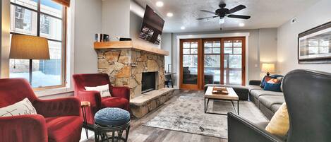 Bright open living room with red accent arm chairs and sliding patio doors to private deck