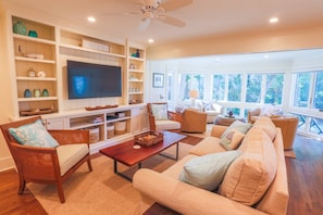The living room features a large screen TV, built-in cabinetry and comfortable coastal furnishings.