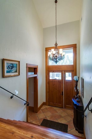 Entryway with high ceilings, wooden doors, and tiled flooring.