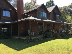 Large porch facing lake with two swings, rocking chairs, outdoor dining.