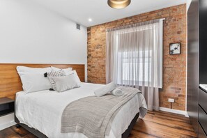 Rest easy in the chic first bedroom housing a queen-size bed with built-in wardrobes.