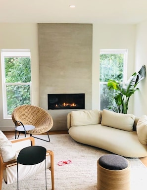 Cozy living room filled with natural light, gas fireplace, and nature vies.