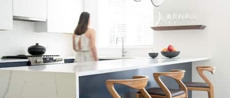 Open modern kitchen with designer stools and lighting.