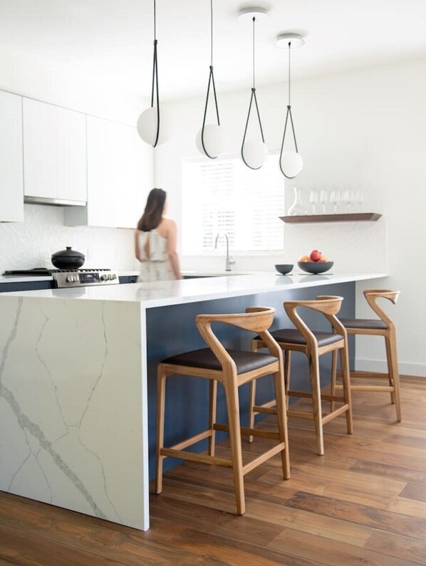 Open modern kitchen with designer stools and lighting.