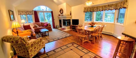 A sunny open concept space with dining table that seats 6 and comfortable furniture that surrounds the fireplace.