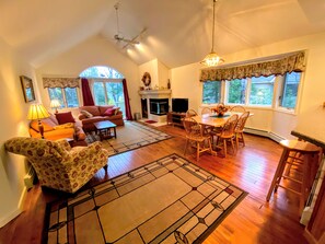 A sunny open concept space with dining table that seats 6 and comfortable furniture that surrounds the fireplace.