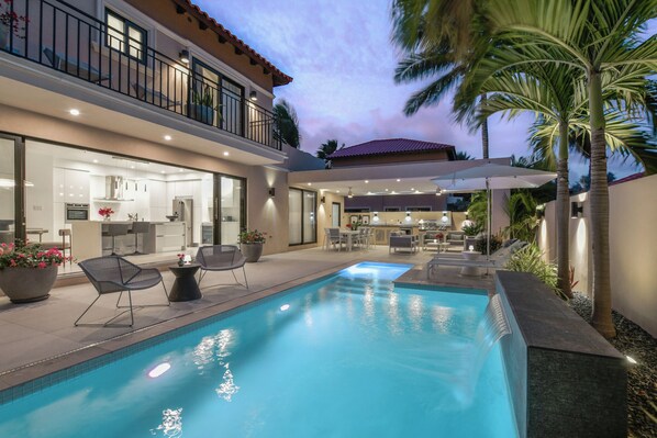 Backyard by night with private pool and gaebo-covered dining, lounging and BBQ 