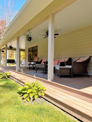 2-sided covered porch with comfy furniture and a porch swing.