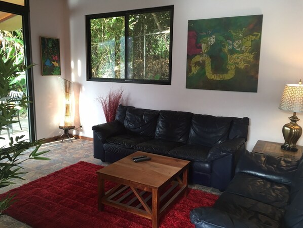 Comfortable Italian leather sofa, love seat, art and sliding glass doors.