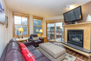 Living area with mounted flat screen TV, gas fireplace and ample seating.