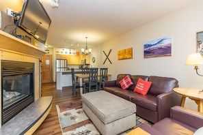 Living area with mounted flat screen TV, gas fireplace and ample seating.