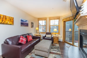 Living area with mounted flat screen TV, gas fireplace and ample seating.