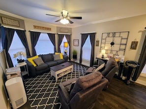 Large open living room with couch, 2 reclining gliders, air purifier and games