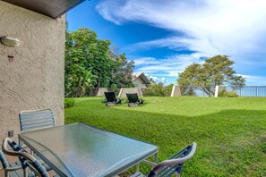 Relax on the shaded patio overlooking rolling green lawns and a glimpse of the ocean, creating a serene outdoor retreat. NAP-B43