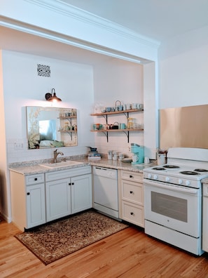 Original wood beam spans across the studio apartment with full kitchen