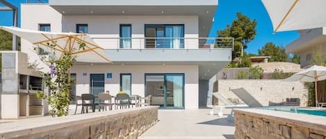 Außenansicht der Luxusvilla Elegance auf der Insel Brac mit Steinstufen, die zu einer Außenterrasse mit Sonnenliegen und einem Swimmingpool führen