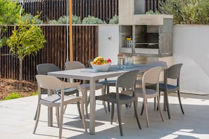 A dining table with 8 chairs and a fireplace on the outdoor terrace of Croatia luxury villa by the sea on the island of Brac