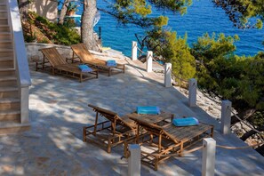 A view of the stone-paved sundeck with sunbeds of the Croatia luxury rent villa Brač