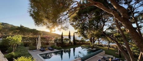 Private heated pool and deck chairs under the trees in a landscaped garden of a Croatia luxury villa Lilly on Brac island