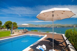 Parasol and sun loungers by the pool on the private terrace of the Croatia luxury villa Trogir 1 with sea view
