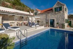 Außenansicht einer luxuriösen Kroatien Familienvilla Murvica mit einer Außenterrasse mit Liegestühlen und einem privaten Pool in Murvica auf der Insel Brac