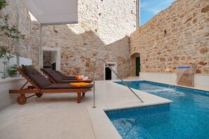 A sunbed with sunbeds next to a private pool on the outdoor terrace of a luxury holiday villa in the center of Bol, Croatia