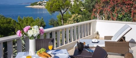 Fenced terrace with rattan lounger and outdoor table and chairs on the property of Croatian luxury private pool villa for vacation and rent