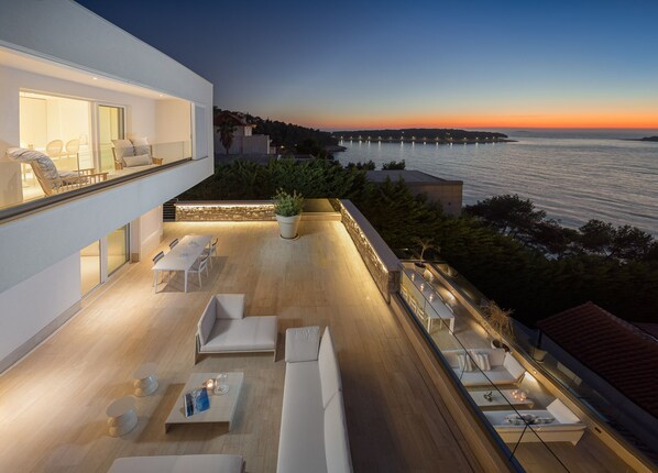 A view of the outdoor terrace with deckchairs and sofas and a view of the sea in Croatia luxury villa for rent Primosten Glamour 