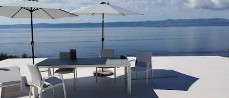 Esstisch und Sonnenschirme im Freien auf der Terrasse der kroatischen Luxusvilla Brac mit Meerblick für den Urlaub