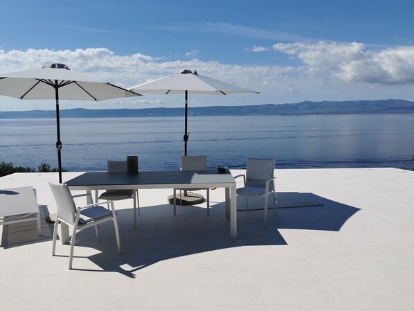 Esstisch und Sonnenschirme im Freien auf der Terrasse der kroatischen Luxusvilla Brac mit Meerblick für den Urlaub